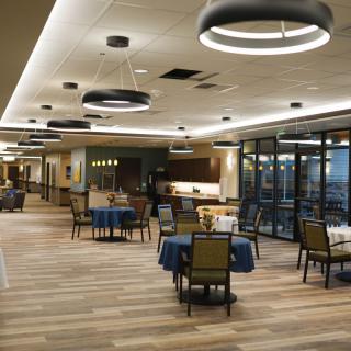 A modern restaurant interior with minimalist design, featuring wood flooring and stylish lighting.
