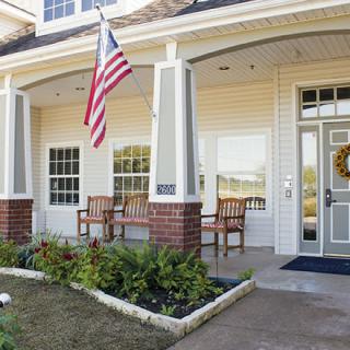 Front porch of a house with an American flag and patio chairs.