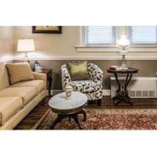 A cozy living room with a beige sofa, patterned armchair, and a coffee table, illuminated by table lamps.