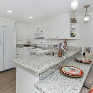 A modern kitchen with white cabinets and granite countertops.