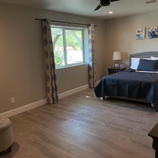 A modern and spacious bedroom with hardwood flooring and natural light.