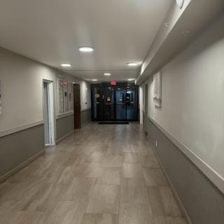 A view of a well-lit hallway with modern decor and a glass entrance at the end.