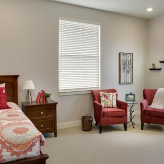 A cozy bedroom with red chairs and a neatly made bed.