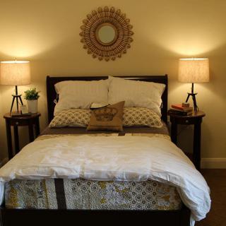 A cozy bedroom with a neatly made bed, flanked by nightstands and warmly lit lamps.