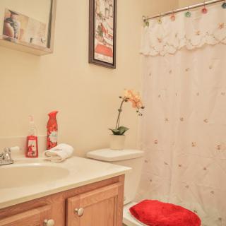 A neatly organized bathroom with a floral theme, featuring a sink, toilet, and shower curtain.