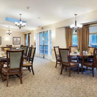 A spacious dining area with elegant tables and chairs, adorned with chandeliers and large windows.
