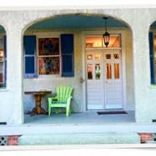 A cozy porch with a green chair and table in front of a double doorway.