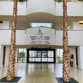 The entrance of a medical center featuring palm trees and modern architecture.