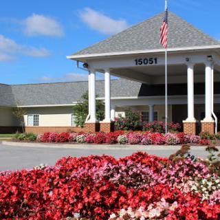 A beautiful building with vibrant flower beds and an American flag in front.