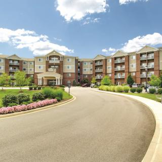 A modern residential apartment complex with a landscaped entrance and clear blue skies.