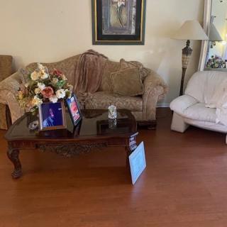 A cozy living room with a sofa, coffee table with flowers, and a painting on the wall.