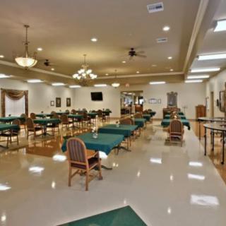 An empty dining room with neatly arranged tables and chairs under warm lighting.