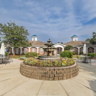 A serene outdoor space featuring a central fountain surrounded by well-maintained gardens and seating areas.