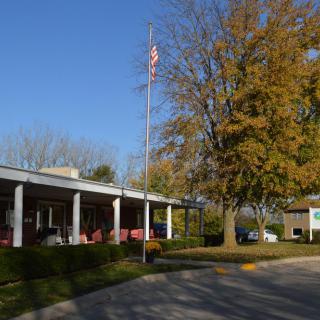 A building with an American flag, surrounded by trees in autumn.