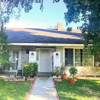 A quaint residential house with a well-maintained front yard and pathway on a sunny day.