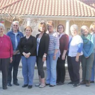 A group of people standing together outdoors, smiling for the photo.