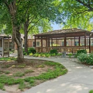 A peaceful outdoor area featuring a gazebo surrounded by lush greenery and a winding walkway.