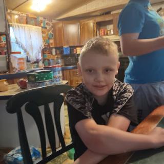 A young boy sitting at a dining table in a cozy kitchen.
