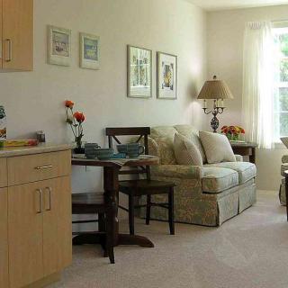 A cozy living room with light-colored furniture and a large window letting in natural light.