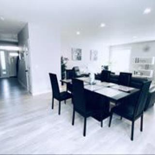 A modern and minimalist dining room with a sleek table and chairs set, featuring bright lighting and contemporary decor.