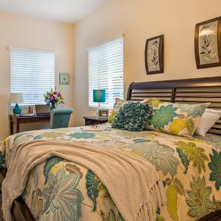 A cozy bedroom with floral bedding and bright natural light.