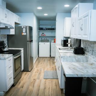 A modern kitchen with white cabinetry and a connected laundry area.