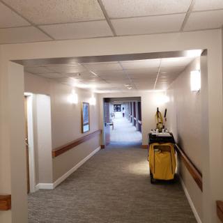 A well-lit hallway featuring a cleaning cart, characterized by a clean and inviting carpet.