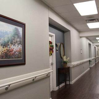 A well-lit hallway with artwork on the wall and doors along the corridor.