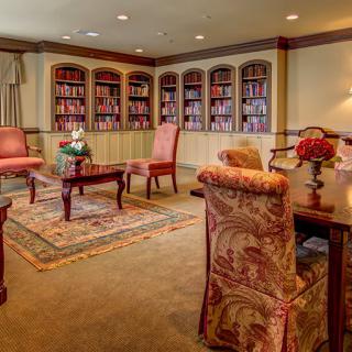 A cozy library reading room with shelves filled with books and elegant furniture.