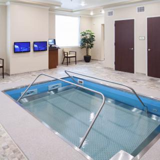 An indoor therapy pool in a healthcare facility, equipped for physical rehabilitation exercises.
