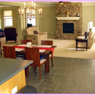Open-concept living and dining area with a central fireplace and elegant chandelier.