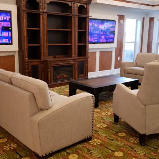 A cozy living room featuring comfortable sofas and chairs arranged around a wooden coffee table, with a large entertainment center and televisions enhancing the space.
