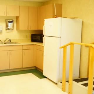 A small kitchen area featuring a refrigerator, cabinets, and a sink.