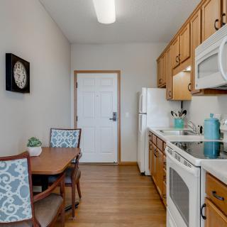 A modern kitchen with wood cabinets, a small dining table, and essential appliances.