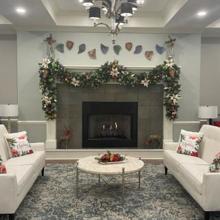 A cozy living room with a decorated fireplace, featuring sofas and a coffee table, ready for the holidays.
