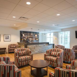 A modern lounge with striped armchairs and a bar counter.