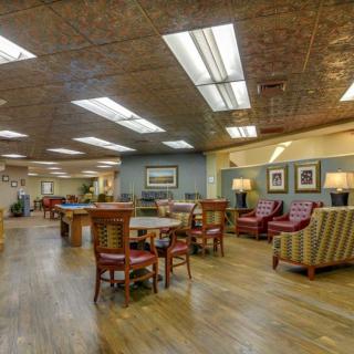 A spacious and well-lit lounge area with various seating arrangements and decorative art on the walls.