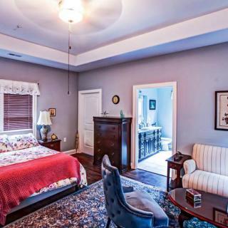A cozy bedroom with a red-accented bed, elegant furniture, and tasteful decor.