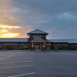 A serene view of a building at sunset, with an empty parking lot.