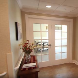 A hallway featuring double doors with a decorative table and vase of flowers.