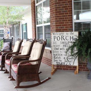 A cozy porch with wicker rocking chairs and a welcoming sign inviting guests to relax.