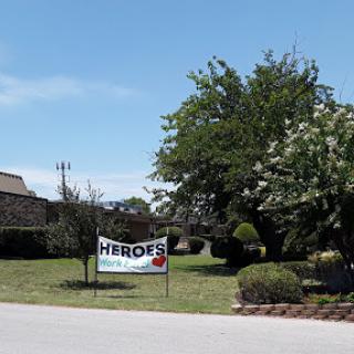 A sign reading 'Heroes' in a grassy area under a blue sky.
