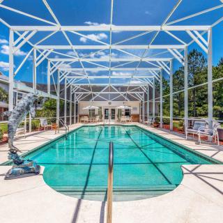 An enclosed swimming pool with a clear blue sky overhead, surrounded by a structured framework.