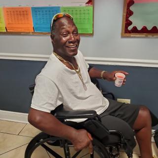 A man in a wheelchair smiling indoors.