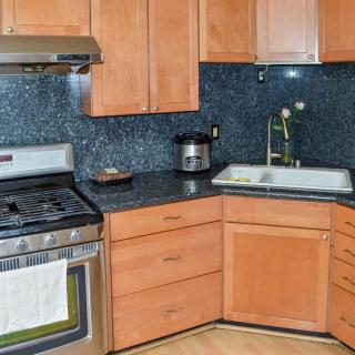 A modern kitchen with wooden cabinets, a stainless steel stove, and a deep sink.