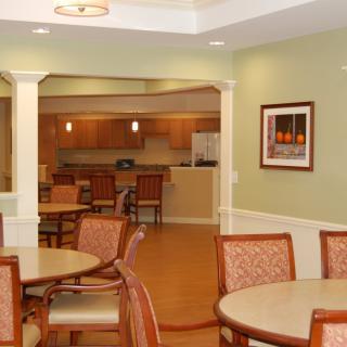 A modern dining area with multiple tables and chairs, adjacent to a kitchen space.