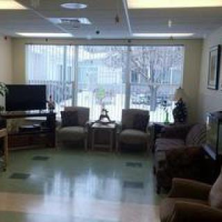A cozy waiting area with several chairs, a television, and large windows letting in natural light.