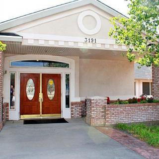 The front entrance of a building with double wooden doors and a brick exterior.