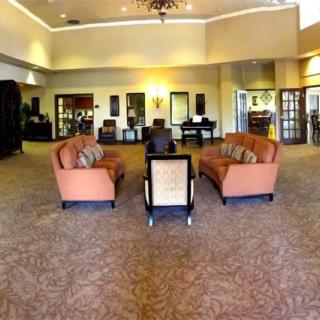 A spacious lobby area with sofas and chairs arranged on a carpeted floor, featuring elegant decor and ceiling lights.
