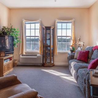 A cozy living room with a sofa, television, and large windows letting in natural light.
